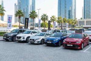 Modern car rental fleet lineup in Dubai setting, various vehicles, including SUVs, sedans, and compact cars parked in a row, brands including Toyota, Hyundai, Nissan, KIA, 