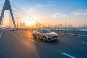 Economy sedan driving across a Dubai bridge at sunrise